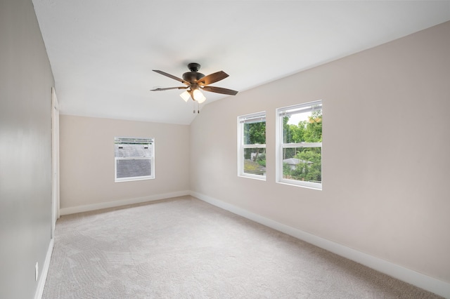 spare room with light colored carpet, lofted ceiling, baseboards, and a ceiling fan
