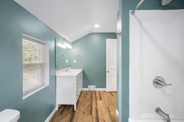 full bathroom featuring vanity, baseboards, wood finished floors, and lofted ceiling