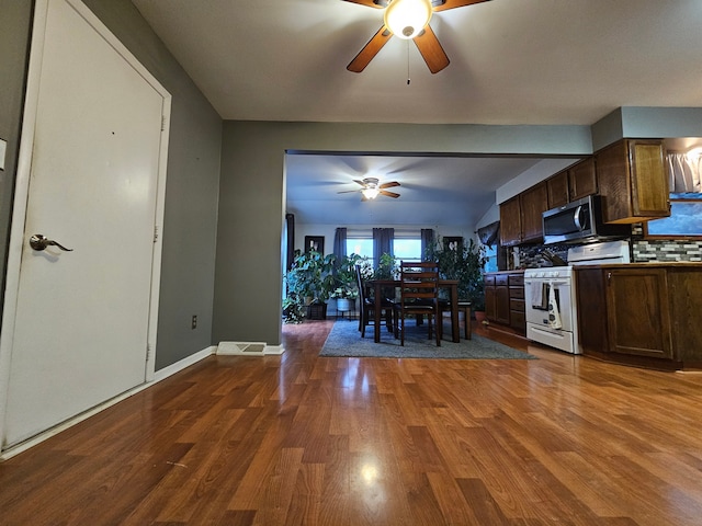 3544 Burnsline Rd, Brown City, MI 48416 - kitchen with wood finished floors, a ceiling fan, white range with electric cooktop, stainless steel microwave, and decorative backsplash