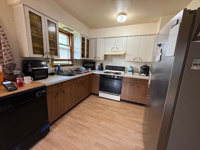 10300 Farrand Rd, Otisville, MI 48463 - kitchen with a sink, gas range oven, under cabinet range hood, light countertops, and light wood-style floors