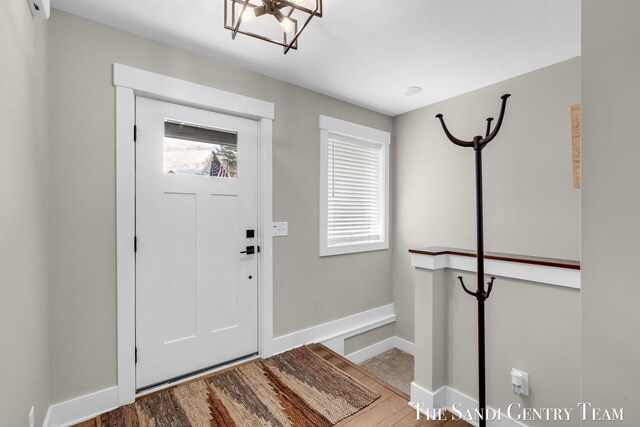 entryway with an inviting chandelier, baseboards, and wood finished floors