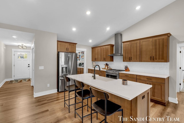 kitchen with a sink, wall chimney exhaust hood, brown cabinets, tasteful backsplash, and appliances with stainless steel finishes