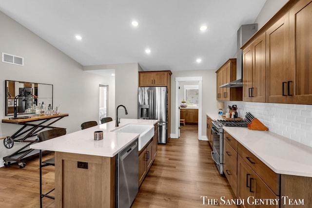 kitchen with a sink, a breakfast bar, visible vents, appliances with stainless steel finishes, and tasteful backsplash