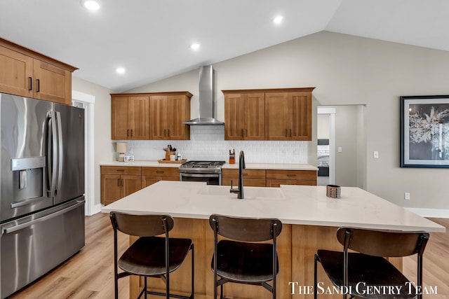 kitchen featuring lofted ceiling, light wood-style flooring, a sink, wall chimney exhaust hood, and stainless steel appliances