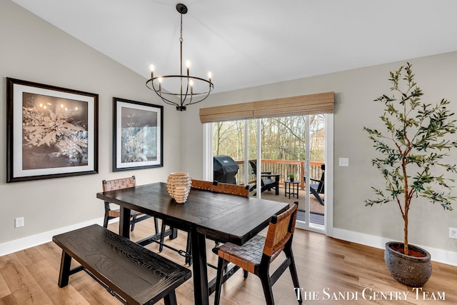 dining room with baseboards, a chandelier, light wood-style flooring, and vaulted ceiling