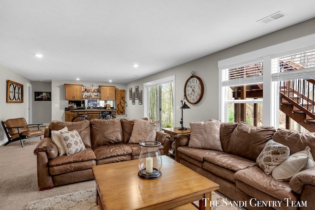 living area featuring recessed lighting, baseboards, visible vents, stairway, and light colored carpet