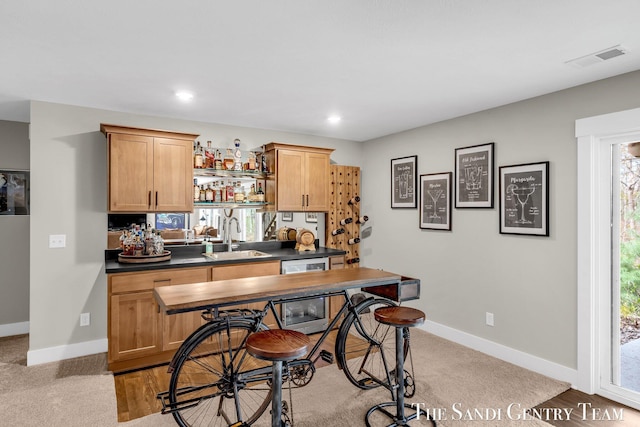 bar featuring baseboards, wine cooler, visible vents, and a sink