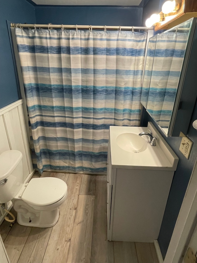 full bathroom featuring a shower with curtain, toilet, wainscoting, vanity, and wood finished floors