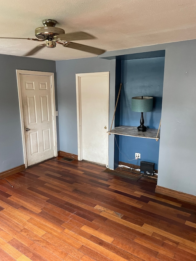 interior space featuring a textured ceiling, baseboards, and wood finished floors