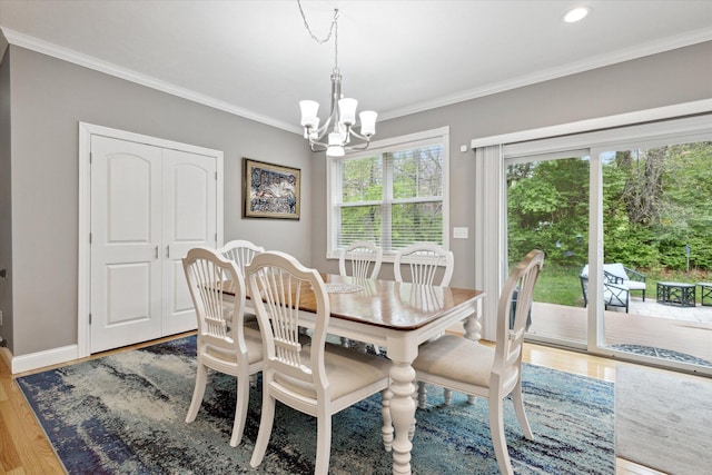 dining area with ornamental molding, a notable chandelier, baseboards, and wood finished floors
