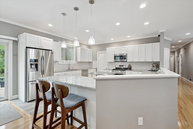 kitchen with a sink, a peninsula, tasteful backsplash, crown molding, and appliances with stainless steel finishes