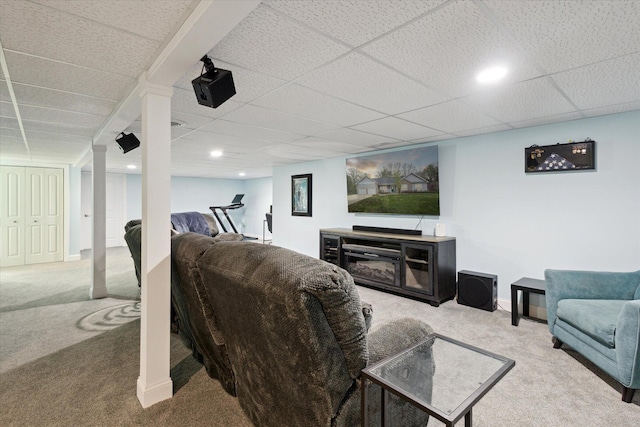 living area featuring baseboards, a drop ceiling, carpet flooring, and a fireplace
