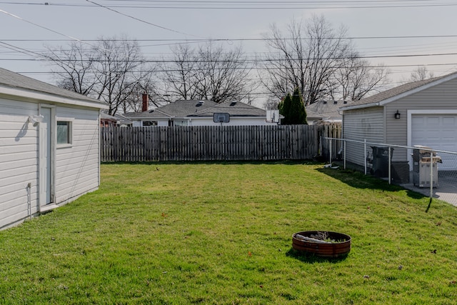 view of yard with a fenced backyard, a garage, and an outbuilding