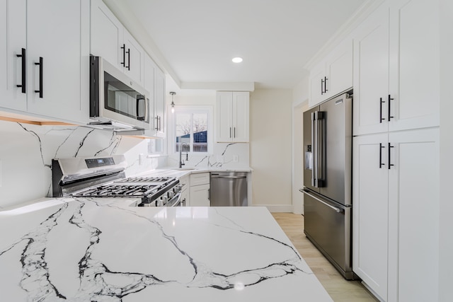 kitchen with a sink, stainless steel appliances, light stone counters, recessed lighting, and white cabinets