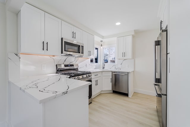 kitchen featuring white cabinets, stainless steel appliances, light stone counters, and recessed lighting