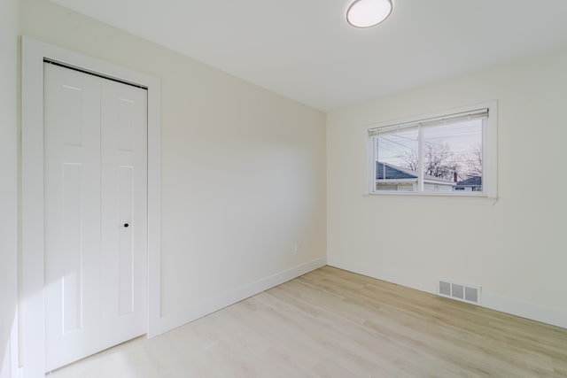 unfurnished bedroom with baseboards, a closet, visible vents, and light wood-style floors