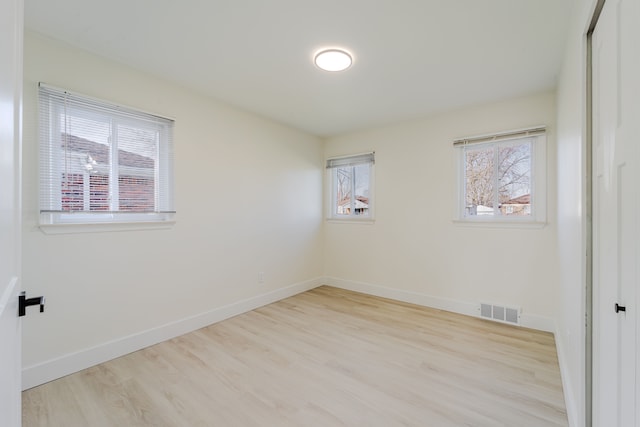 spare room with baseboards, visible vents, and wood finished floors
