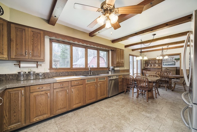 kitchen with appliances with stainless steel finishes, brown cabinets, beamed ceiling, and a sink