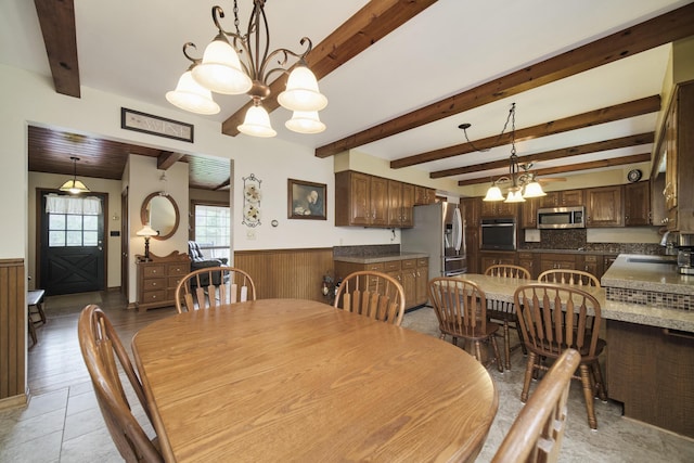 dining room featuring wood walls, beamed ceiling, a notable chandelier, and a wainscoted wall