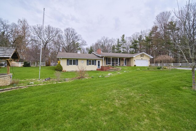 ranch-style house featuring fence, an attached garage, a front lawn, and a chimney