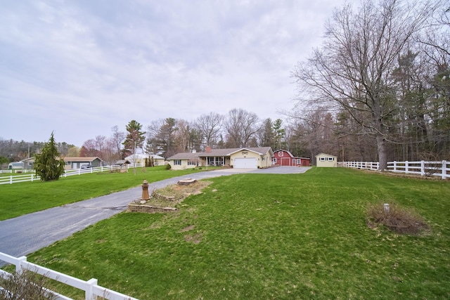 view of yard featuring aphalt driveway, fence, and a garage