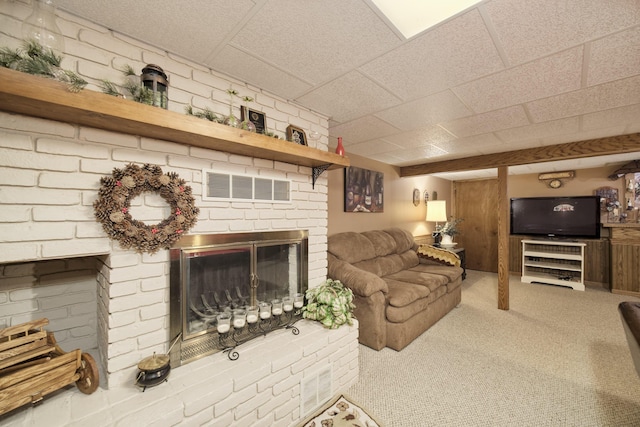 carpeted living room featuring a drop ceiling, a fireplace, and visible vents