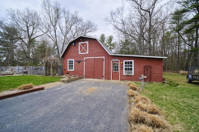 garage featuring aphalt driveway, fence, and cooling unit