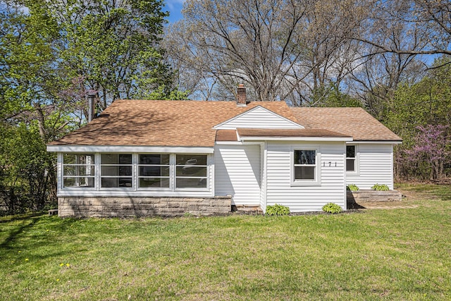 view of front of home featuring a front lawn, roof with shingles, and a chimney