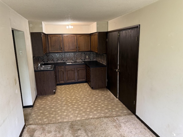 8367 S Douglas Rd, Bedford, MI 48144 - kitchen with stovetop, a sink, dark countertops, dark brown cabinetry, and decorative backsplash