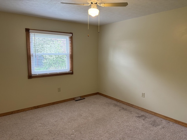 spare room with light carpet, baseboards, a ceiling fan, and visible vents