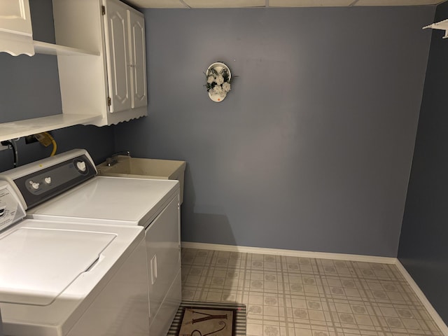 clothes washing area with baseboards, a sink, tile patterned floors, separate washer and dryer, and cabinet space