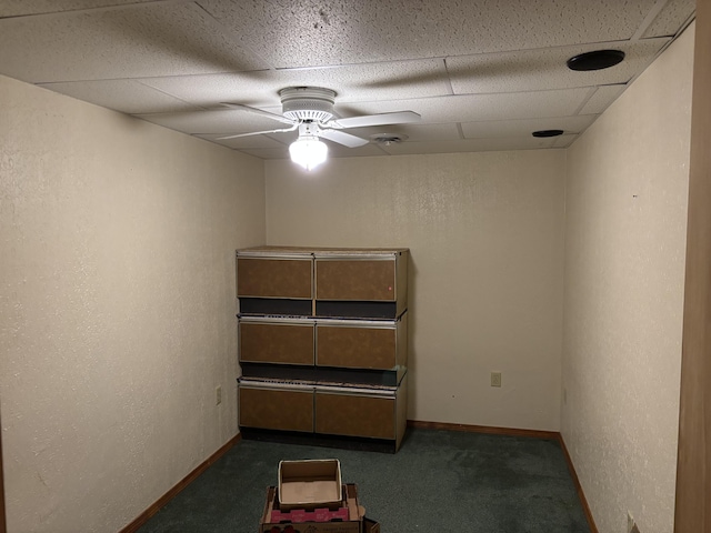 empty room with carpet, a drop ceiling, a ceiling fan, baseboards, and a textured wall
