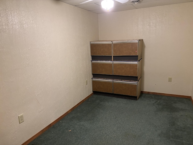 unfurnished room featuring baseboards and dark carpet