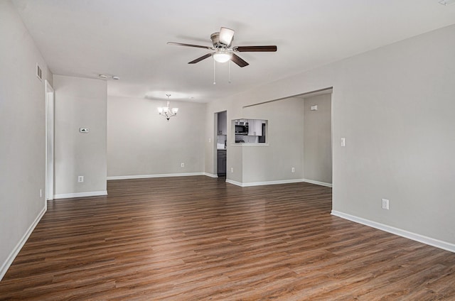 empty room with a chandelier, a ceiling fan, wood finished floors, and baseboards