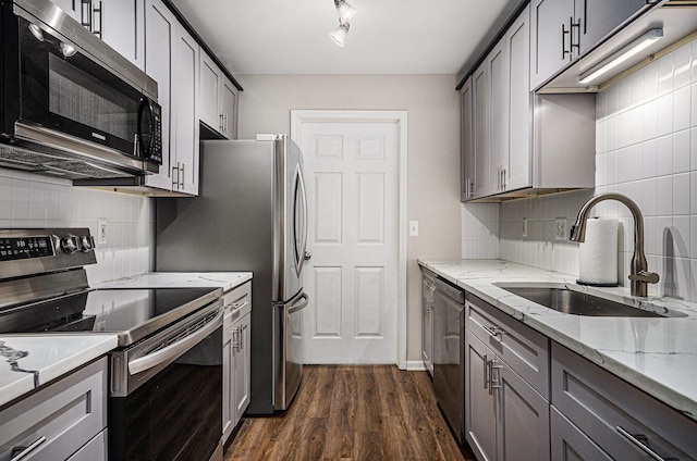 kitchen featuring appliances with stainless steel finishes, a sink, dark wood finished floors, and decorative backsplash