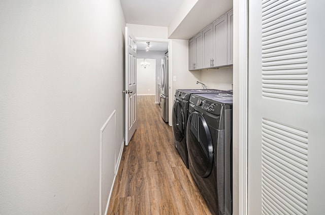 laundry area with cabinet space, independent washer and dryer, wood finished floors, baseboards, and a chandelier