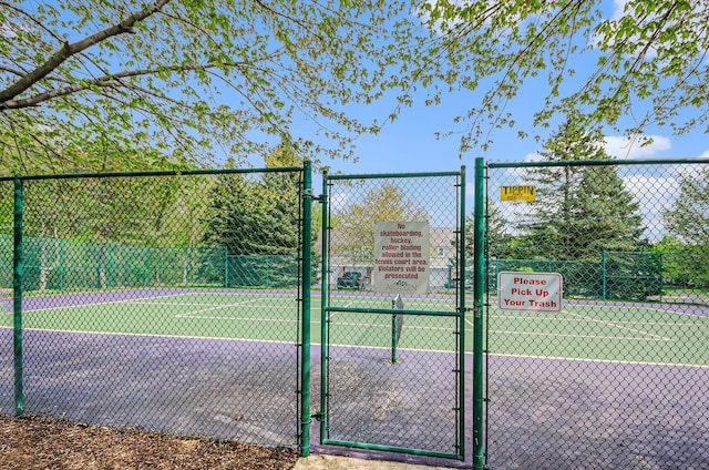 view of tennis court featuring a gate and fence