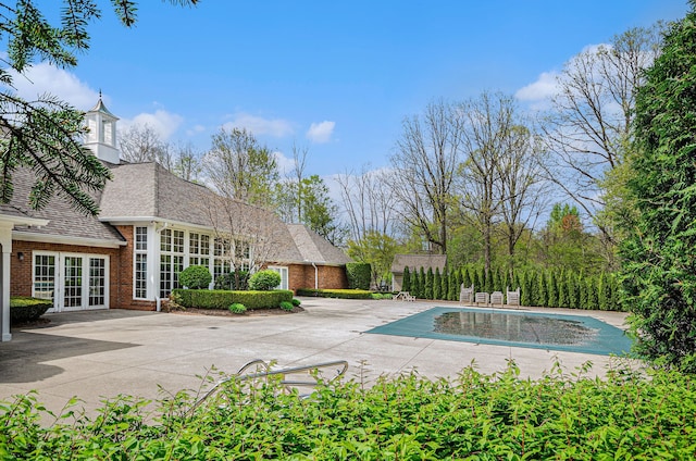 view of swimming pool featuring french doors, a patio, and a covered pool