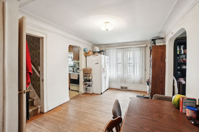 933 Cameron Ave, Pontiac, MI 48340 - dining room featuring arched walkways, light wood-style flooring, and baseboards