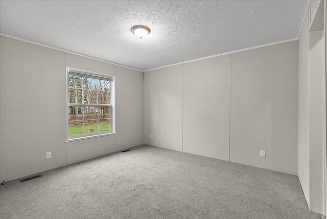 carpeted spare room featuring crown molding, a textured ceiling, and visible vents