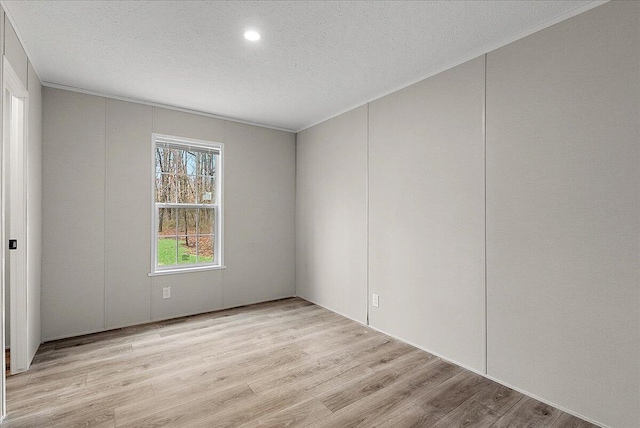 empty room with recessed lighting, crown molding, light wood-type flooring, and a textured ceiling
