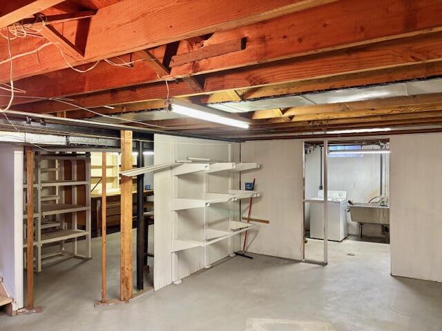 below grade area featuring washing machine and clothes dryer and a sink