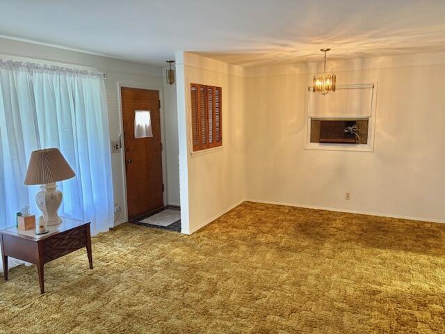 entryway with baseboards, carpet floors, and a notable chandelier