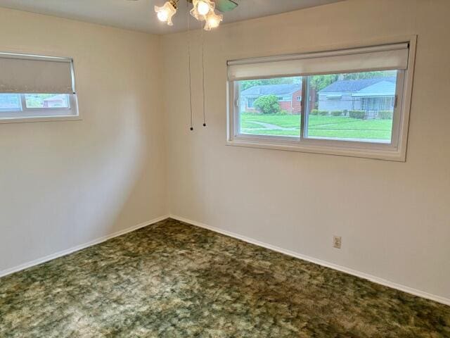 carpeted empty room featuring a wealth of natural light, baseboards, and a ceiling fan