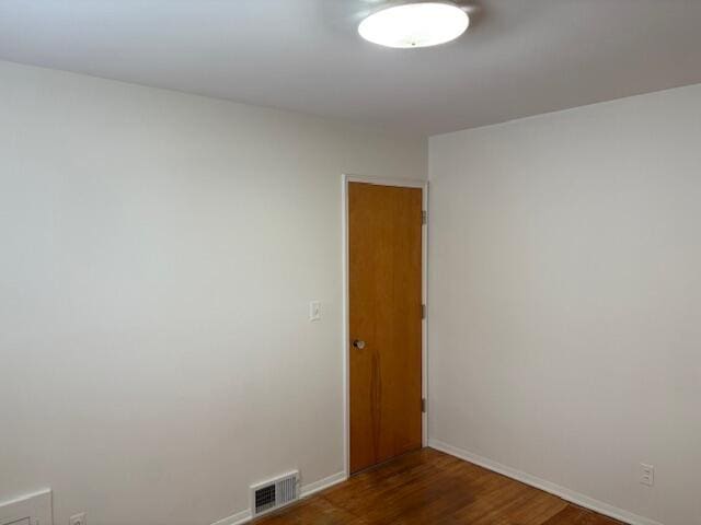 unfurnished room with visible vents, baseboards, and dark wood-style floors