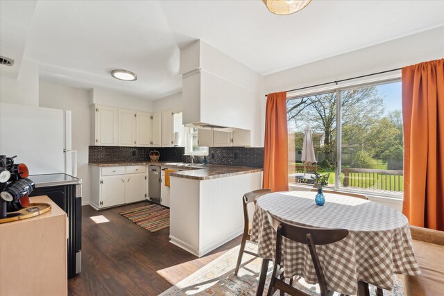 kitchen with dishwasher, decorative backsplash, dark wood finished floors, and dark countertops