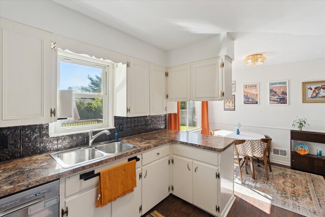 kitchen featuring stainless steel dishwasher, a sink, decorative backsplash, and white cabinetry