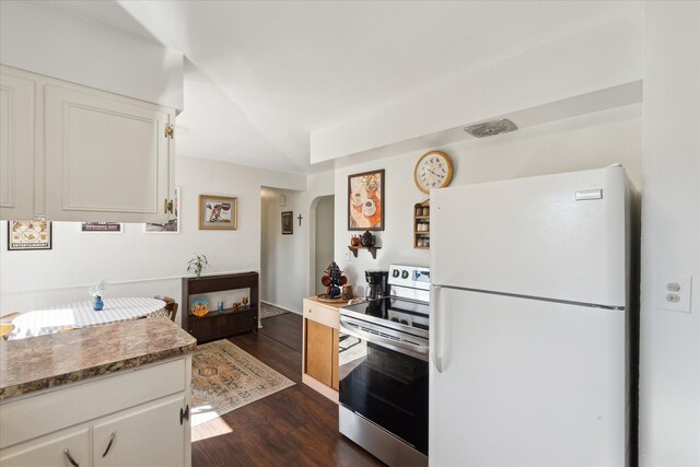 kitchen featuring freestanding refrigerator, stainless steel electric range, arched walkways, dark wood-type flooring, and white cabinetry