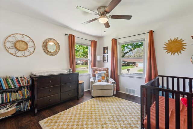 bedroom with a crib, wood finished floors, and a ceiling fan