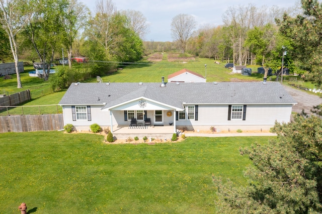 rear view of property with fence, a patio, and a lawn